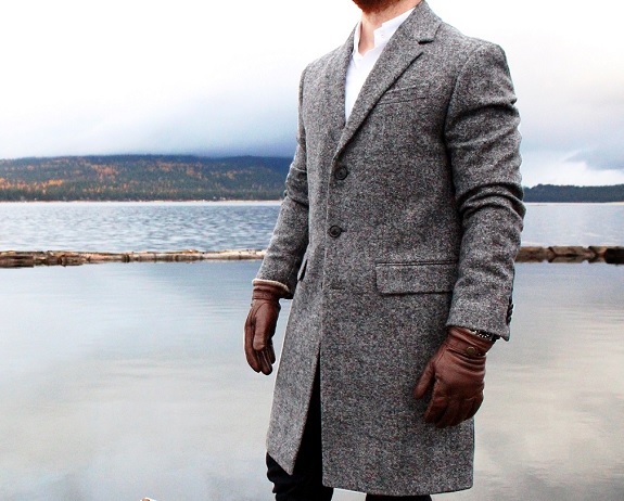 man in topcoat in front of lake