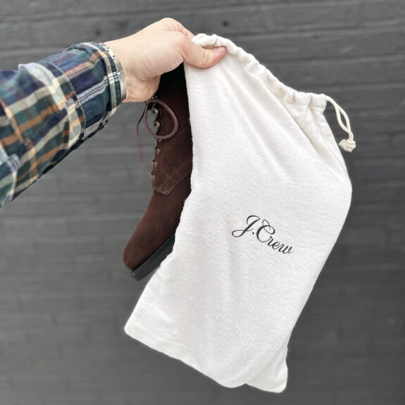 J. Crew Field Boots in Brown Suede being held by hand with flannel shoe bag