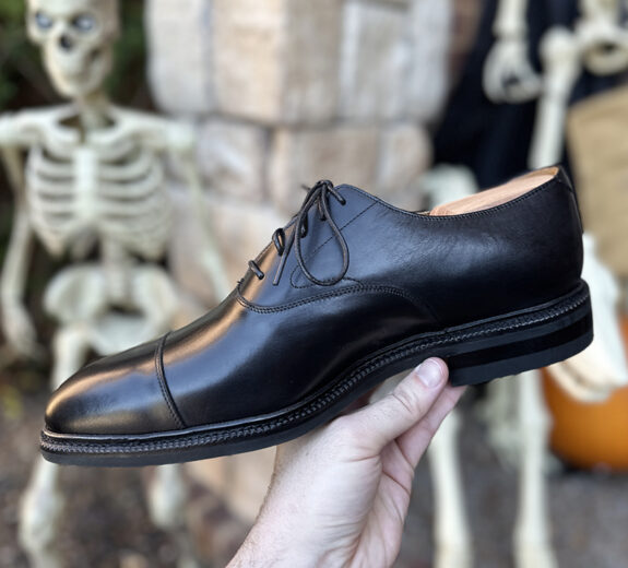 Meermin Cap Toe Oxfords in hand with skeletons behind.